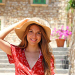 Beautiful tourist girl with hat and red dress posing on cozy ita