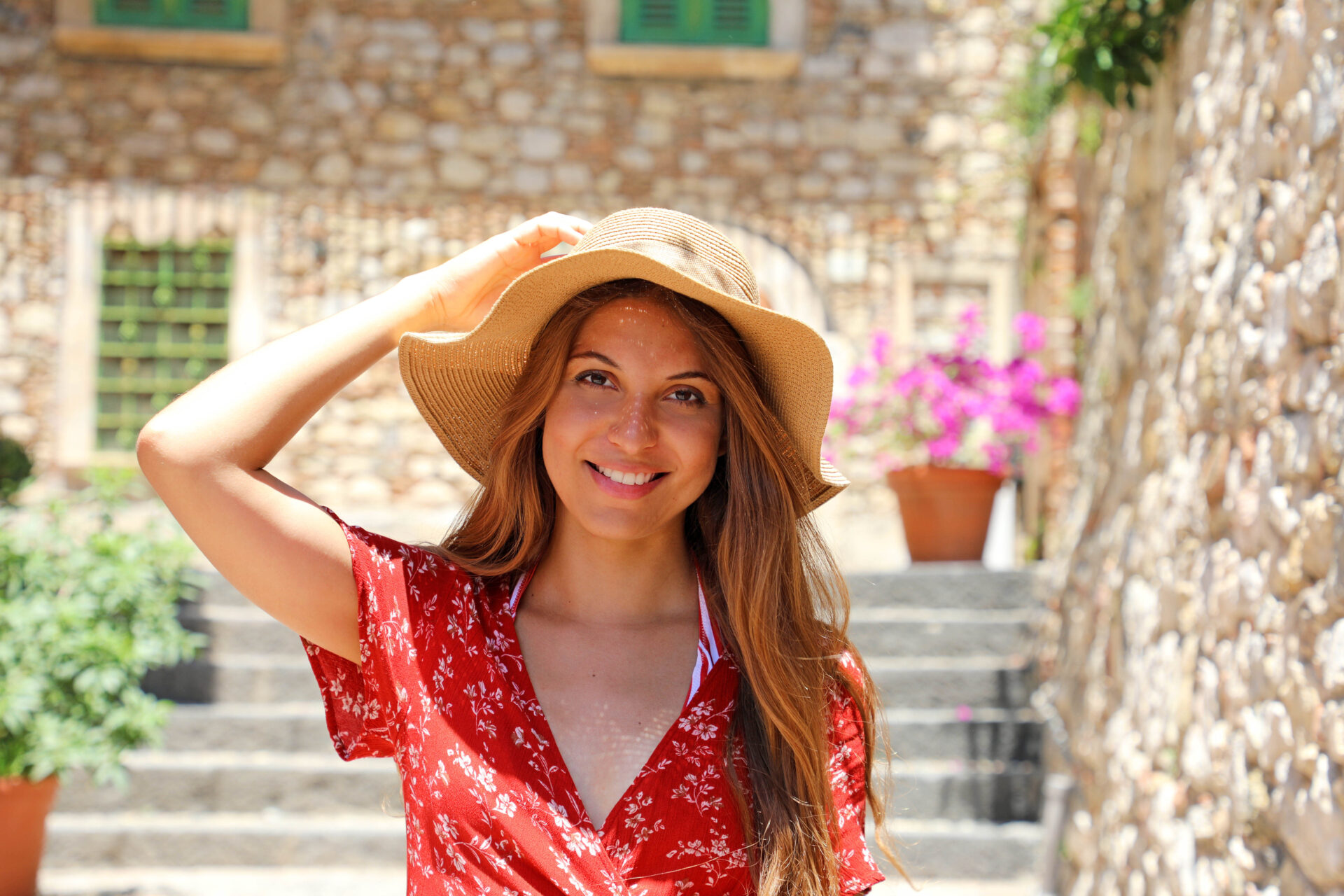 Beautiful tourist girl with hat and red dress posing on cozy ita